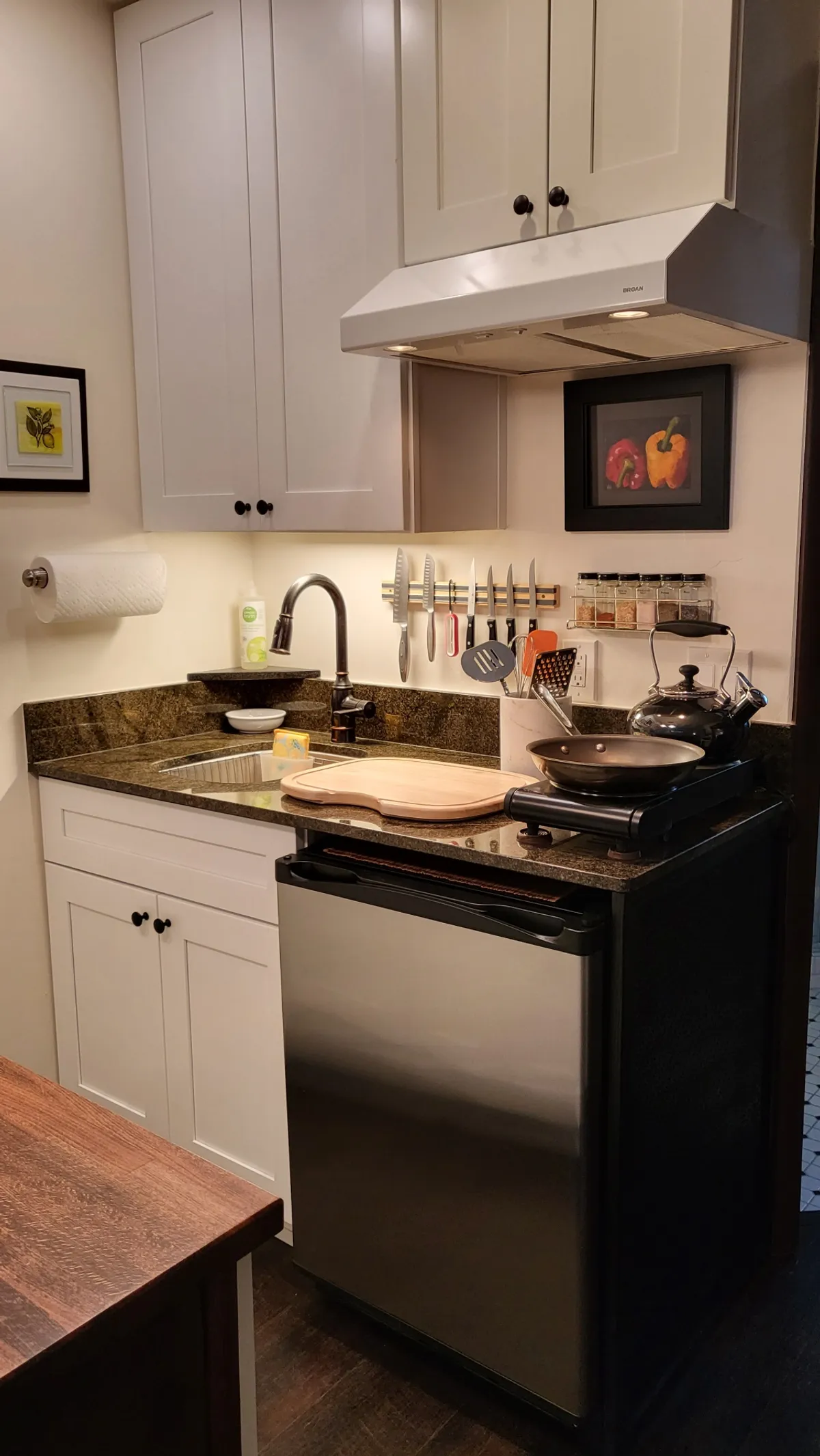 A cozy, well-lit kitchen interior highlights a granite countertop, stainless steel appliances, a knife rack, and colorful artwork. The space feels family-friendly and functional, suitable for meal prep or gathering with loved ones. The granite countertop and modern appliances hint at an efficient setup for cooking and easy clean-up.