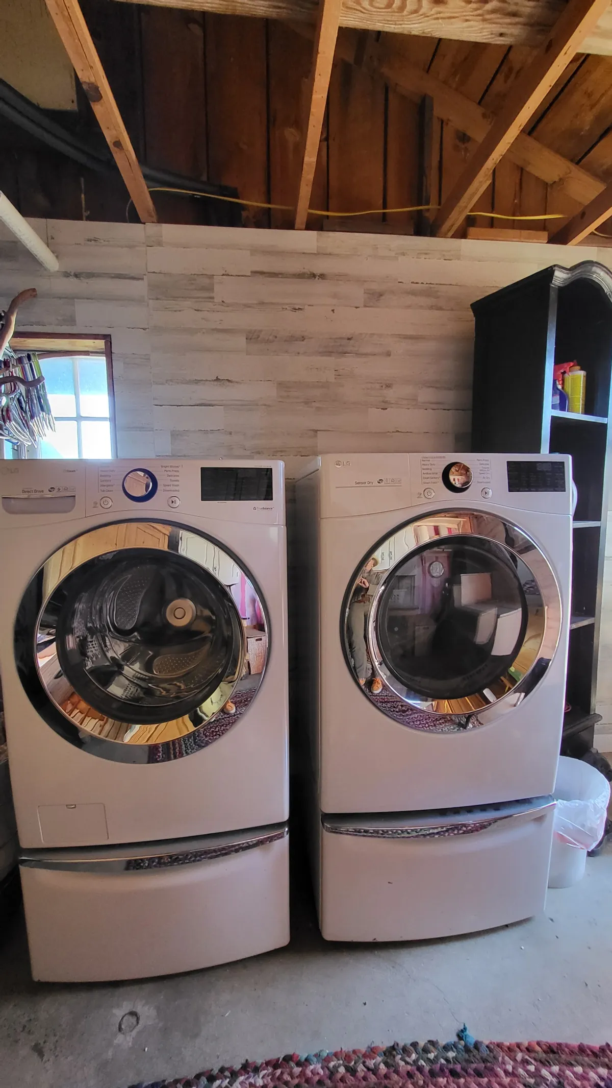 The image showcases a practical laundry area within the Rock House Dells Studio Retreat, featuring a washing machine and drying machine set against a textured wall. A cozy rug softens the space, and the overall vibe is inviting and homely, suggesting convenience and the comforts of daily living while away from home.